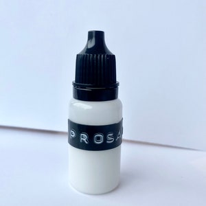 May include: A small white bottle with a black dropper top and a black label that says "PROSA".