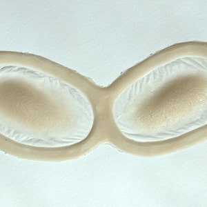 May include: A pair of beige silicone eye molds for creating prosthetic effects.