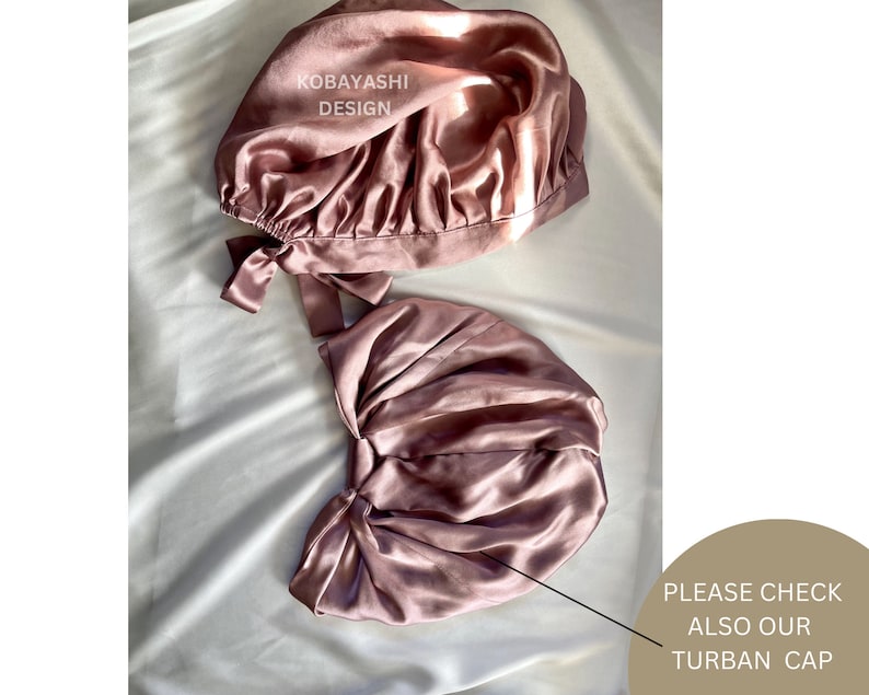 Op de afbeelding: Twee roze satijnen slaapmutsen met een strik aan de zijkant. De tekst "KOBAYASHI DESIGN" is zichtbaar op de bovenste muts. De tekst "PLEASE CHECK ALSO OUR TURBAN CAP" is zichtbaar in de rechterbenedenhoek van de afbeelding.
