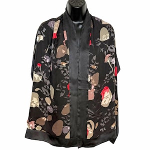 May include: A black open-front kimono featuring a floral pattern in shades of red, tan, and grey. The garment has a solid black satin-like trim along the front opening and the bottom hem, with a smooth texture and a relaxed, flowing silhouette.