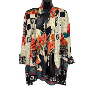 May include: A long-sleeved open-front cardigan featuring a cream base with a multi-colored pattern of black checkerboard squares, orange floral motifs, and geometric shapes. The garment has a draped collar and cuffs with a black and white square border.