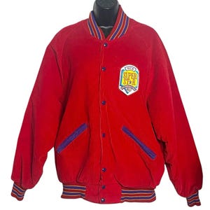 May include: A red corduroy jacket with a button-up front, featuring a colorful "SUPER STAR" patch. The jacket has blue and purple accents on the pockets, collar, and cuffs. A vintage varsity style jacket.