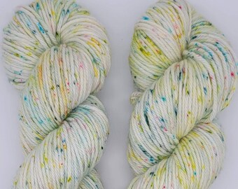 Puede incluir: Dos ovillos de hilo en un patrón moteado con una base blanca y toques de amarillo, verde, azul y rosa.