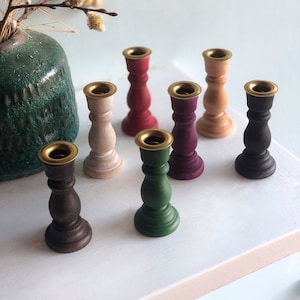 Small 3" turned birch wood candlesticks with brass safety shield on rim for chime candles and other mini candles with a diameter of .5". Photo shows available colors (natural, unfinished, black, white, green, red and purple).