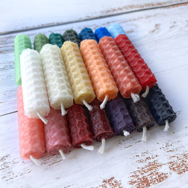 Small 2" pure beeswax rolled candles for meditations, intention setting and witchcraft spells stacked in a pile showing the rainbow of available colors.