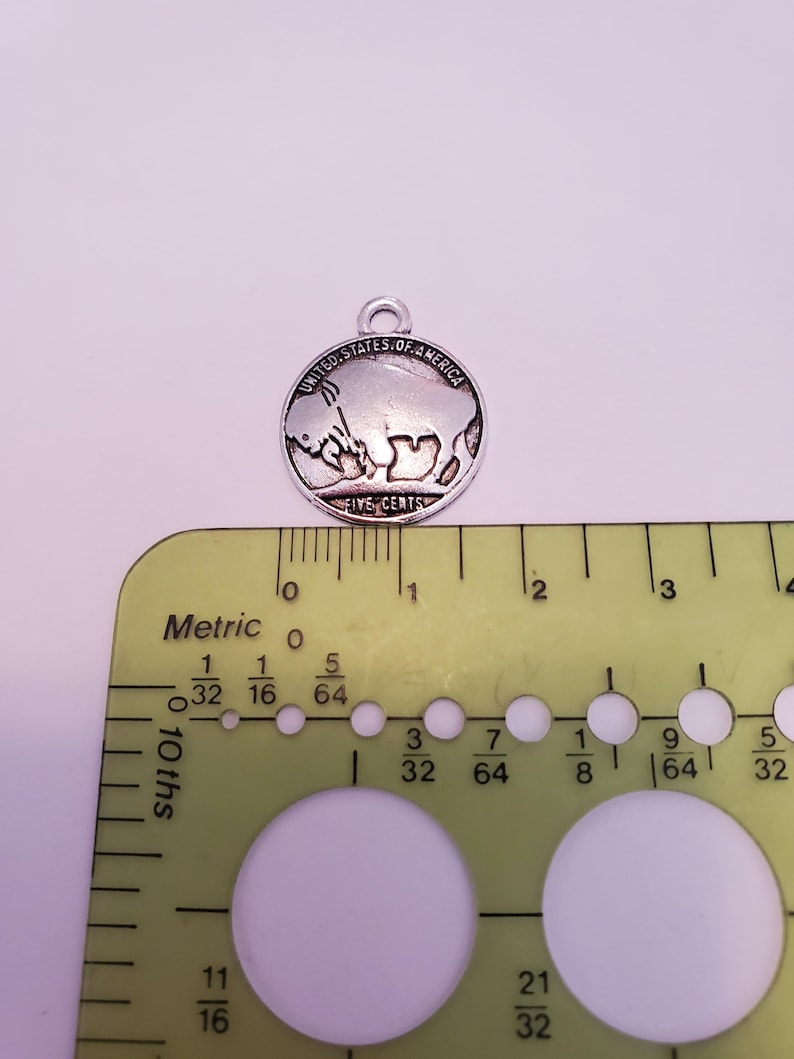 May include: A silver charm in the shape of a United States five-cent coin featuring a buffalo. The coin is approximately 1.9 cm in diameter.
