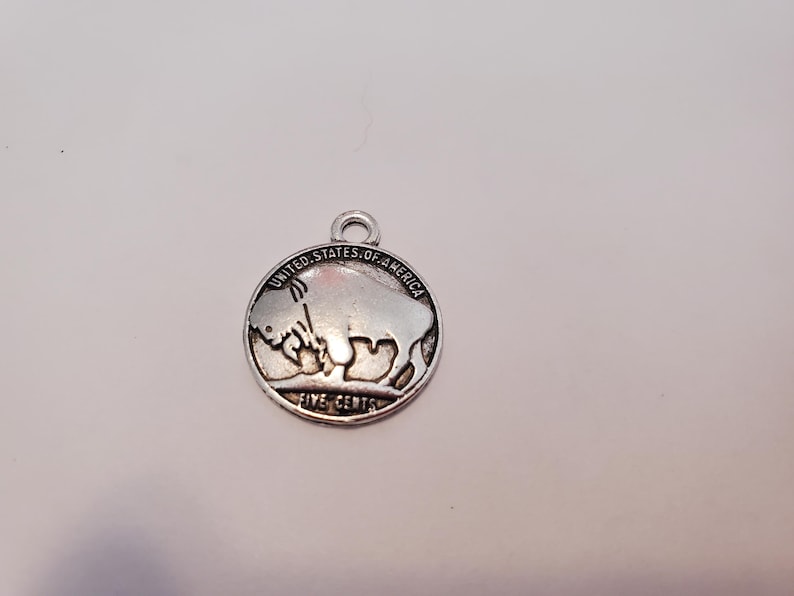 May include: Silver charm featuring a buffalo nickel design with the text "United States of America" and "Five Cents".
