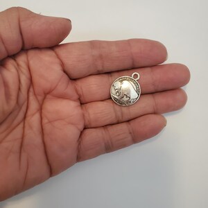 May include: Silver charm featuring a buffalo with the words "United States of America" and "Five Cents" around the edge.