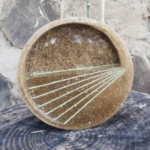 May include: A round, brown tray with a green geometric design. The tray is made of wood and resin and has a natural, rustic look.