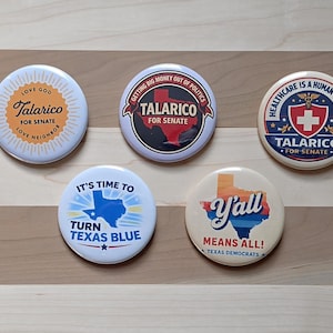 May include: A collection of five round political campaign buttons. The buttons feature text such as "Talarico for Senate", "It's Time to Turn Texas Blue", and "Y'all Means All! Texas Democrats". The buttons are white, red, blue, and orange.