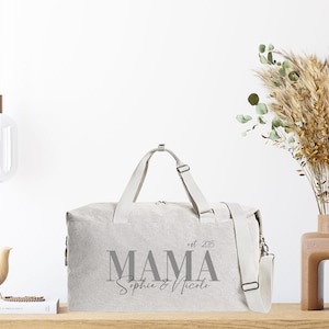 Puede incluir: Una bolsa de viaje de lona gris con el texto "MAMA est. 2015 Sophie & Nicolo" impreso en la parte delantera.