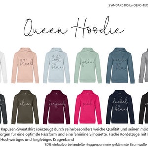 May include: A selection of Queen Hoodies in various colors, including white, pink, and gray. Each hoodie features a drawstring hood and the word "Queen" in cursive. The hoodies are made of a soft material.