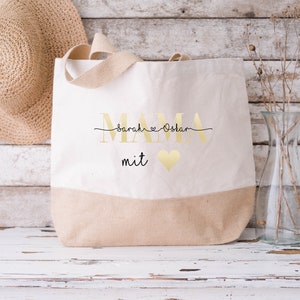 Pode incluir: Uma bolsa de lona bege com letras douradas que dizem "MAMA Sarah & Oskar mit" e um cora&ccedil;&atilde;o dourado.