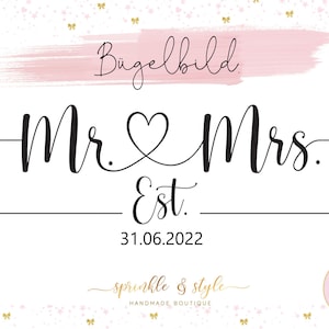 May include: A black and white iron-on design with the text "Mr. & Mrs. Est. 31.06.2022" and a heart symbol. The design is on a white background with a pink watercolour wash at the top and a scattering of gold stars.