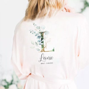 Può includere: Una vestaglia di raso rosa con un motivo floreale e il nome "Leonie" e la data "BRAUT - 15.08.2020" stampati sul retro.