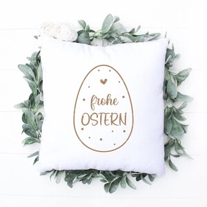 May include: White pillow with a brown Easter egg design and the text "frohe Ostern" in German.