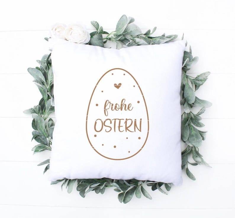 May include: White pillow with a brown Easter egg design and the text "frohe Ostern" in German.