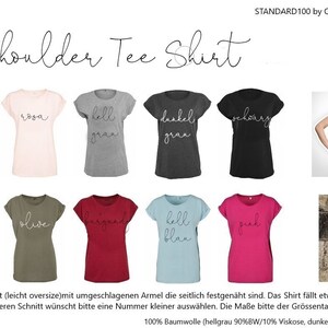May include: A collection of shoulder tee shirts in various colors, including white, pink, gray, black, navy, olive, burgundy, light blue, and fuchsia. Each shirt has a different word in cursive script. The text "Shoulder Tee Shirt" is at the top.