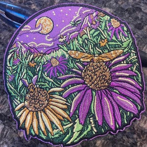 Könnte beinhalten: Lila und gelber gestickter Patch mit einer Nachthimmel-Szene mit einem Mond, Sternen und einer Libelle, die über einem Blumenfeld fliegt.