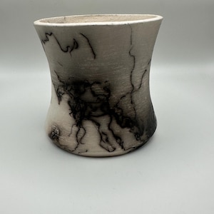 Könnte beinhalten: Eine handgefertigte Keramikvase mit einer einzigartigen, organischen Form. Die Vase ist überwiegend cremeweiß mit dunklen, komplizierten Mustern, die an Blitze erinnern. Das Design ist eine Mischung aus natürlichen und künstlerischen Elementen, für die Inneneinrichtung.