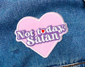 May include: Pink heart-shaped patch with the text "Not today Satan" in purple letters with a small red heart between "Not" and "today".