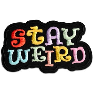 Puede incluir: Parche bordado con la frase "STAY WEIRD" en letras coloridas de estilo burbuja. El texto es rojo, amarillo, morado, verde y rosa, con un contorno negro. El parche tiene un borde negro.