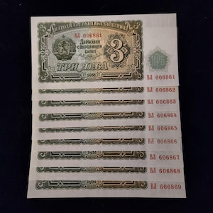 May include: A stack of eight vintage Bulgarian banknotes, each featuring a red and green design with the text "Народна Република България" and "Три лева" (People's Republic of Bulgaria and Three Leva). The serial numbers on the bills range from 606861 to 606869.