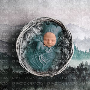May include: A newborn baby is sleeping in a woven basket, wrapped in a teal blanket and wearing a blue knitted hat. The background is a watercolor painting of mountains and a misty forest.