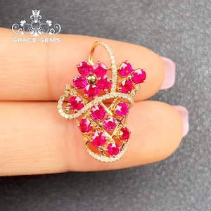 May include: A gold pendant featuring a cluster of ruby red gemstones set in a delicate gold design. The pendant is shaped like a bouquet of flowers.