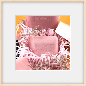Puede incluir: Dos cajas de terciopelo rosa con el texto "GRACEGEMS" est&aacute;n anidadas en papel de arrugas rosa. Las cajas est&aacute;n rodeadas de delicadas flores rosas.