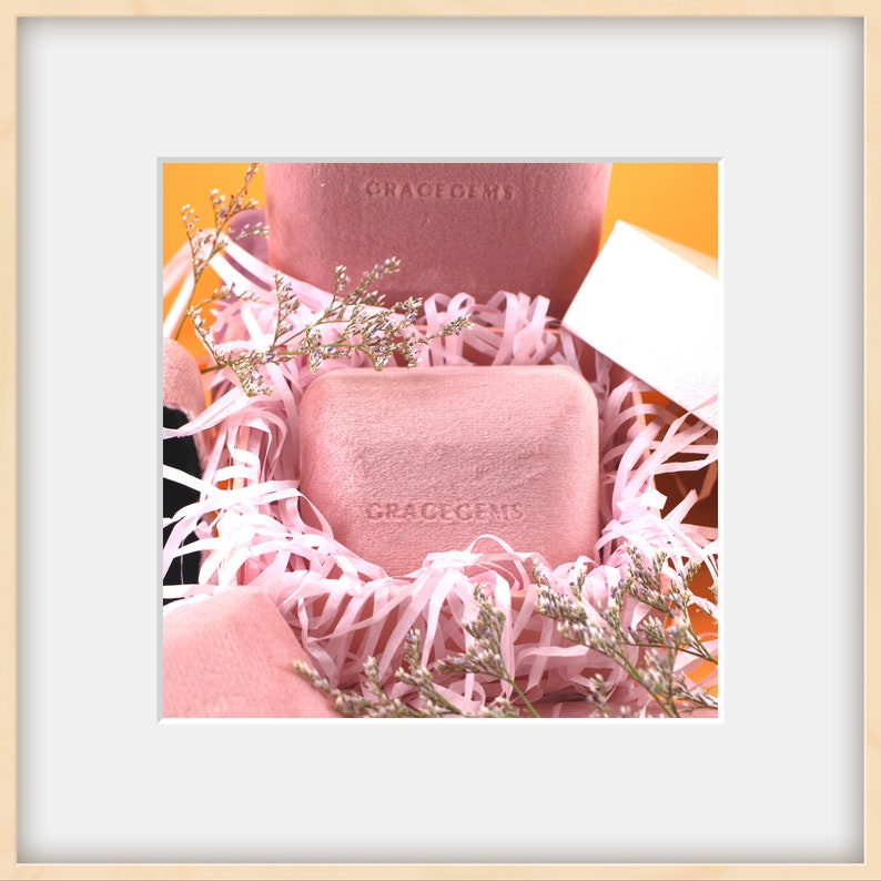 Puede incluir: Dos cajas de terciopelo rosa con el texto "GRACEGEMS" est&aacute;n anidadas en papel de arrugas rosa. Las cajas est&aacute;n rodeadas de delicadas flores rosas.