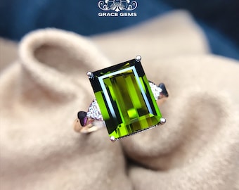 Può includere: Un anello d'argento con una pietra preziosa verde a taglio smeraldo e piccoli accenti di diamanti.