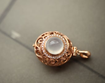 May include: A delicate gold pendant with a white gemstone set in a filigree design. The pendant features a round, white stone surrounded by smaller diamonds.