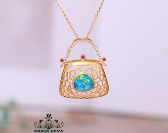 May include: A gold necklace with a pendant shaped like a handbag. The handbag is made of a delicate, openwork design and features a blue opal gemstone in the center. The pendant is accented with small pink gemstones.