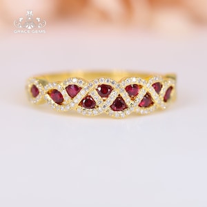 May include: A gold band ring with a braided design featuring red ruby and clear diamond stones.