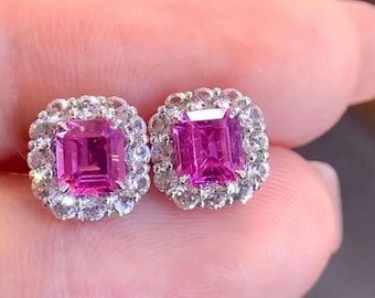 May include: A pair of pink sapphire earrings with a halo of smaller diamonds set in silver.