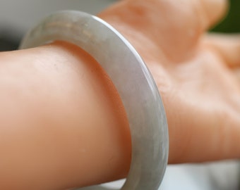 Könnte beinhalten: Ein hellgrünes Jade-Armband. Das Armband ist glatt und poliert, mit einem dezenten Glanz.