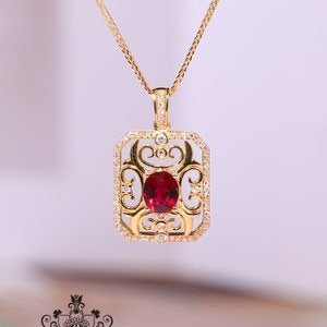 May include: A gold pendant necklace with a red gemstone set in a filigree design. The pendant is surrounded by smaller clear gemstones.
