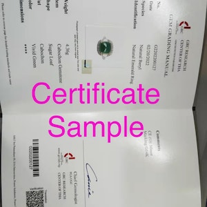 May include: A certificate of authenticity for a natural emerald ring. The ring is set in 14K gold and features a vibrant green cabochon emerald. The certificate includes the date, gem grading manual number, species, identification, and comments. The certificate is signed by a chief gemologist.