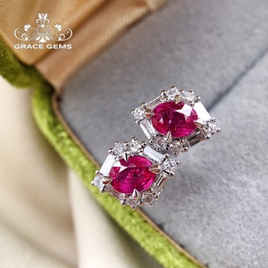 May include: A pair of ruby and diamond earrings. The earrings are set in a hexagonal shape with a round ruby in the centre and smaller diamonds surrounding it.