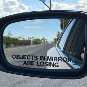 May include: A rearview mirror with a sticker that reads "Objects in mirror are losing".