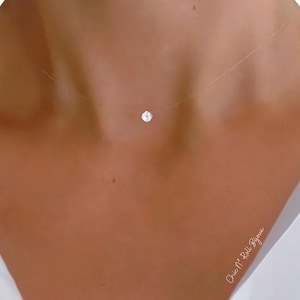 Puede incluir: Un collar tipo gargantilla de hilo de nailon transparente con un único colgante de piedra blanca pequeña, redonda y de talla brillante, centrado en la base del cuello. El cordón invisible crea un efecto de piedra flotante.