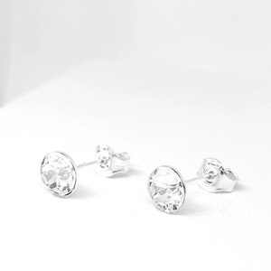 May include: A pair of silver stud earrings with clear round crystal stones.