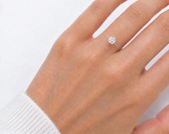 May include: A clear, thin, flexible band ring featuring a single, small, round, brilliant-cut white gemstone set in the center. The ring is worn on a finger, and the text Chic N' Roll Bijoux is printed in white at the bottom of the image.