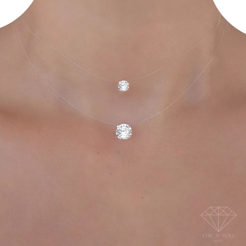 May include: A delicate, two-layered, clear necklace with a small and a larger clear crystal pendant.