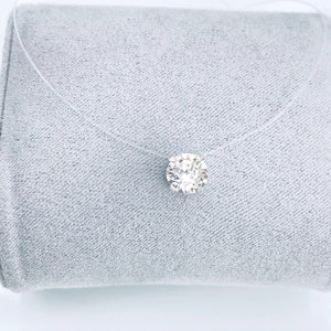 May include: A clear, thin chain necklace with a single, round, clear crystal pendant.