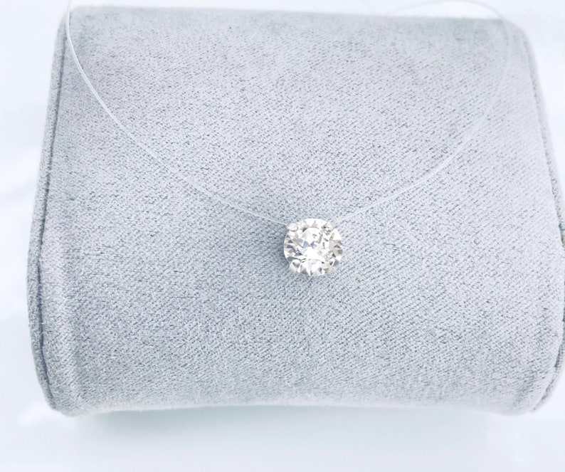 May include: A clear, thin chain necklace with a single, round, clear crystal pendant.