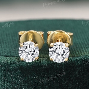 May include: A pair of gold stud earrings with clear round cubic zirconia stones.