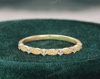 May include: A yellow gold band ring featuring a repeating pattern of marquise-shaped metal segments alternating with small, clear, round-cut stones. The ring has a polished finish and a delicate, thin profile, showcasing a consistent, symmetrical design.