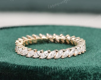 May include: A gold eternity band featuring a continuous row of marquise-cut clear stones set in a shared prong setting. The ring displays a repeating pattern of elongated, pointed gemstones that encircle the entire circumference of the metal band.